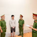 Điều tra viên thi hành lệnh bắt bị can để tạm giam đối với Huỳnh Thanh Huy. (Ảnh: TTXVN phát)