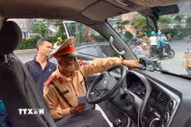 Lực lượng Cảnh sát giao thông kiểm tra thiết bị giám sát hành trình lắp trên phương tiện kinh doanh vận tải. (Ảnh: Trung Nguyên/TTXVN)