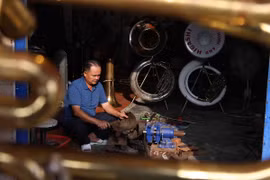 "Điểm riêng của nghề làm kèn đồng Phạm Pháo là hầu hết công đoạn đều được thực hiện thủ công. Những ống đồng được cán phẳng, gò tay thành một chiếc kèn và chỉ sử dụng máy uốn tự chế, máy tiện cho các chi tiết và công đoạn khó. (Ảnh: Minh Đức/TTXVN)