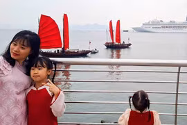 Chụp ảnh cùng thuyền ba vách buồm đỏ truyền thống ven bờ vịnh Hạ Long được nhiều du khách ưa thích.(Nguồn: CTTĐT )