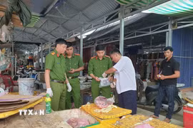 Đoàn kiểm tra lấy mẫu giám định tại sạp thịt của tiểu thương ở chợ xã Vĩnh Viễn. (Ảnh: TTXVN phát)