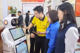 Cán bộ Trung tâm phục vụ hành chính công xã Quỹ Nhất hướng dẫn người dân thao tác trên Robot Lễ tân AI. (Ảnh: Công Luật/TTXVN)