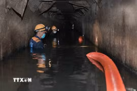 Ngâm mình dưới dòng nước đen ngòm để hút sạch bùn thải, khơi thông dòng chảy cho Thủ đô. (Ảnh: Phan Phương/TTXVN)