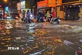 Người dân di chuyển trong điều kiện ngập nước do mưa lớn chiều tối ngày 1/10. (Ảnh: Hồng Đạt/TTXVN)