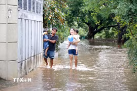 Người dân tại điểm ngập sâu tại phường Bình Thuận (Lâm Đồng) di chuyển đến nơi khác để đảm bảo an toàn. (Ảnh: Nguyễn Thanh/TTXVN)
