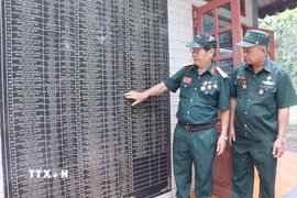 Cựu chiến binh Vũ Đức Ninh cùng đồng đội xem lại tên những người đồng đội đã mất trong chiến tranh được khắc tên trang trọng tại nhà bia tưởng niệm tại phường Hố Nai, thành phố Đồng Nai. (Ảnh: Lê Xuân/TTXVN)