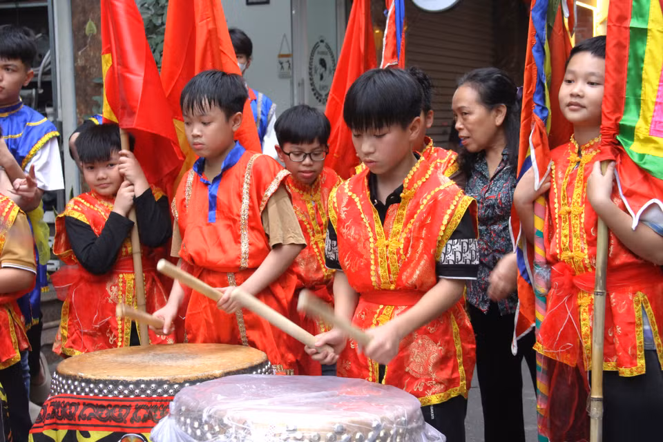 Các em nhỏ cũng được mặc những trang phục đầy màu sắc, đánh trống, phất cờ theo đoàn rước "ông lợn". (Ảnh: Hồng Ngọc/Vietnam+)
