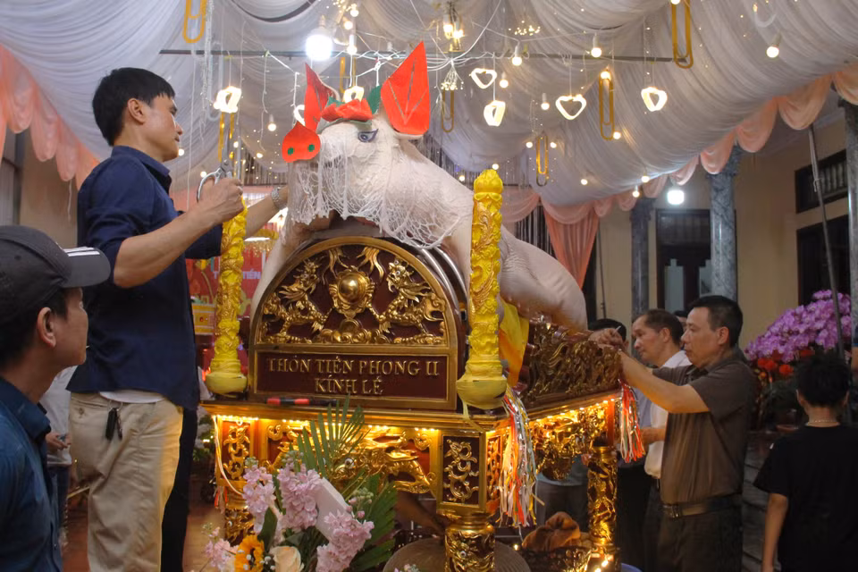 Nhiều người dậy từ 3h sáng tất bật chuẩn bị cho lễ rước "ông lợn". Công đoạn trang trí "ông lợn" thường mất khoảng từ 2 đến 3 tiếng. Riêng những tấm giấy màu, hoa, phụ kiện được người dân chuẩn bị trong suốt nửa tháng qua. (Ảnh: Hồng Ngọc/Vietnam+)