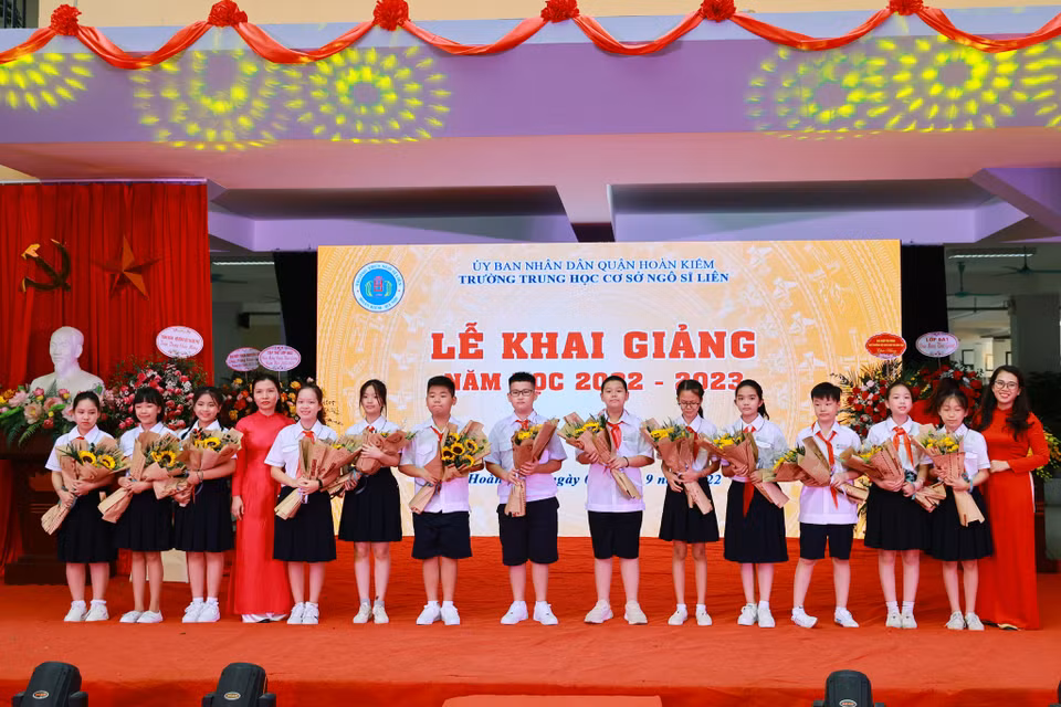Các em học sinh đại diện học sinh khối lớp 6 nhận hoa từ nhà trường, bắt đầu năm học mới đầy hứng khởi và tràn đầy năng lượng. (Ảnh: Hoài Nam/Vietnam+)