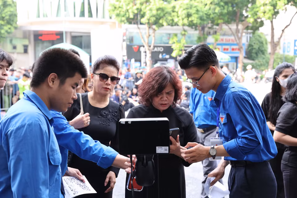Đoàn thanh niên hướng dẫn người dân quét mã QR. (Ảnh: Vietnam+)