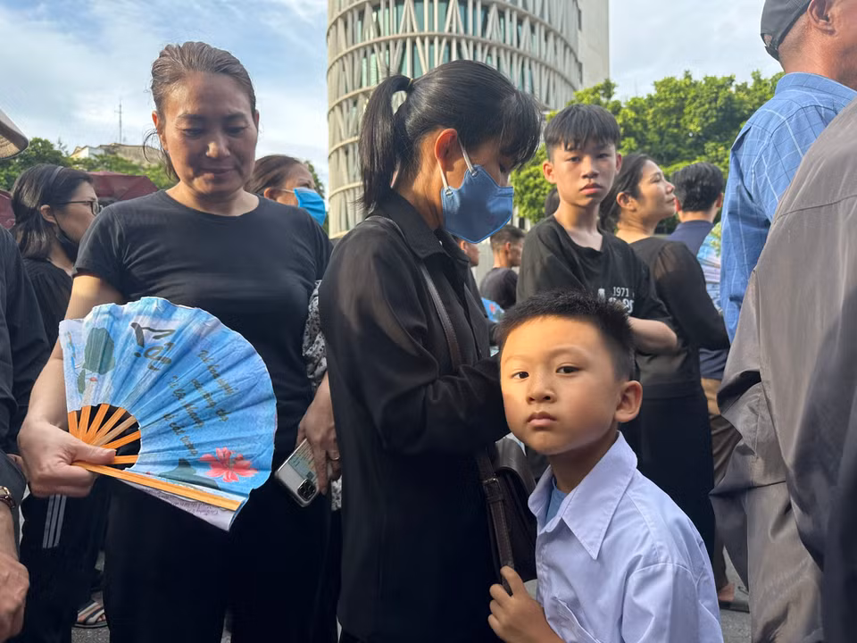 Em bé đi theo mẹ cũng mong được vào viếng Tổng Bí thư. (Ảnh: Vietnam+)