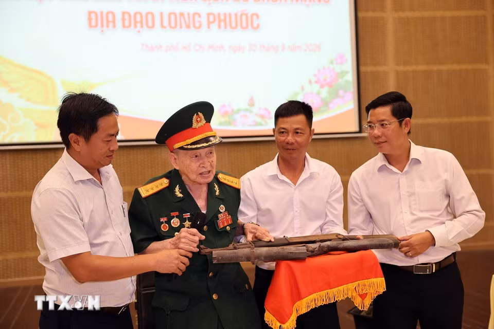 Anh hùng LLVTND, Đại tá Nguyễn Văn Tàu (bí danh Tư Cang, nguyên Cụm trưởng Cụm tình báo H63 huyền thoại) trao tặng 2 khẩu súng. (Ảnh: Đoàn Mạnh Dương/TTXVN)