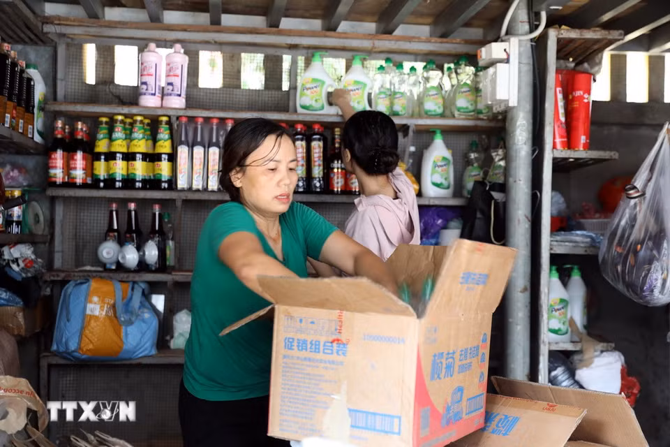 Tiểu thương chợ Giếng Vuông, phường Kỳ Lừa, sắp xếp đồ đạc để di chuyển tài sản ra khỏi khu vực ngập sâu. (Ảnh: Văn Đạt/TTXVN)