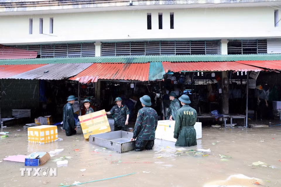Cán bộ chiến sỹ Bộ Chỉ huy Quân sự tỉnh Lạng Sơn giúp tiểu thương di chuyển tài sản ra khỏi khu vực ngập sâu. (Ảnh: Văn Đạt/TTXVN)