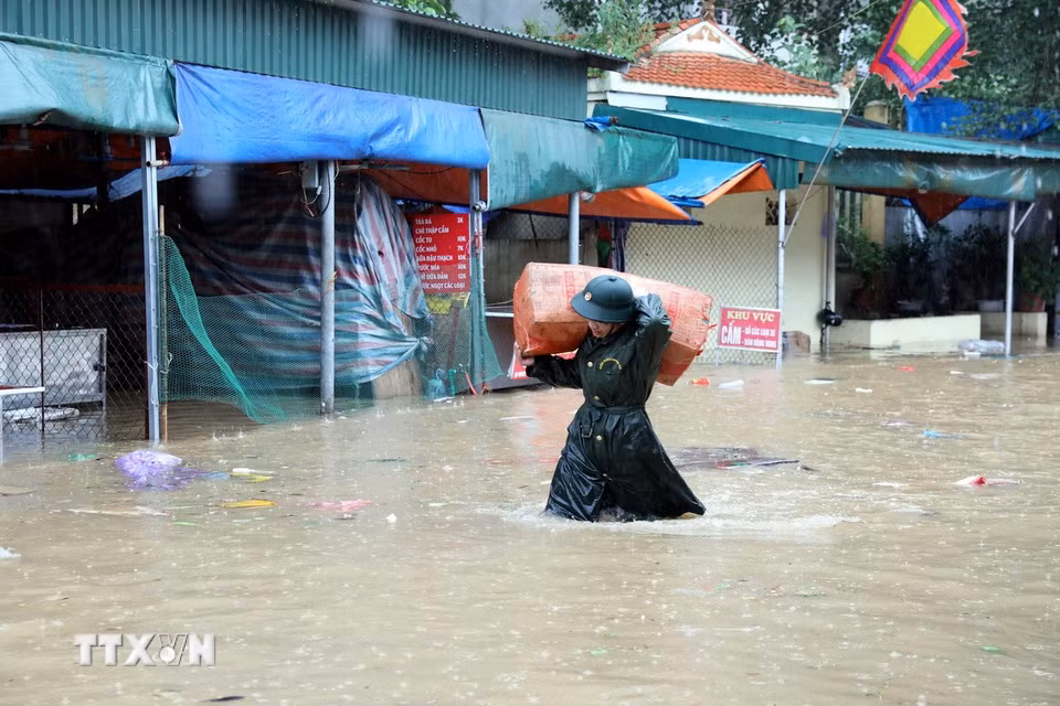 Cán bộ chiến sỹ Bộ Chỉ huy Quân sự tỉnh Lạng Sơn giúp tiểu thương di chuyển tài sản ra khỏi khu vực ngập sâu. (Ảnh: Văn Đạt/TTXVN)