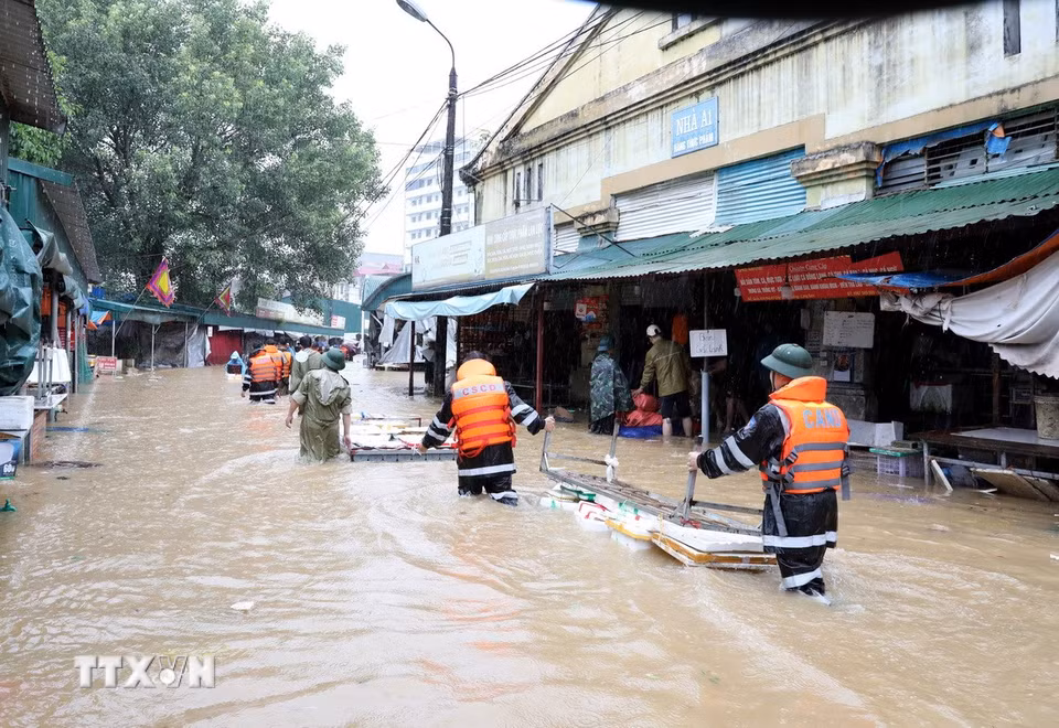 Cán bộ chiến sỹ Công an tỉnh Lạng Sơn giúp tiểu thương di chuyển tài sản ra khỏi khu vực ngập sâu. (Ảnh: Văn Đạt/TTXVN)