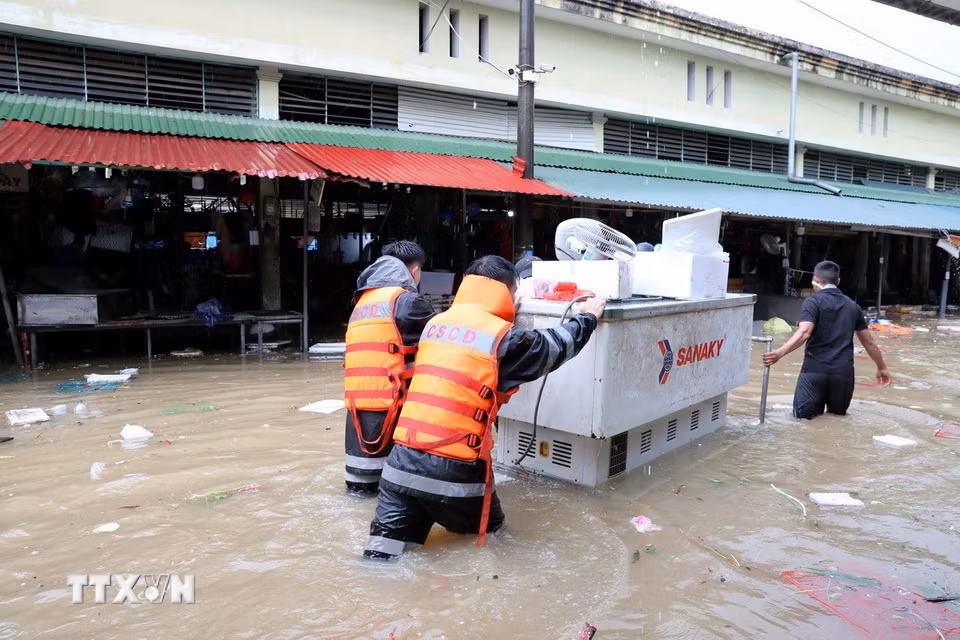 Cán bộ chiến sỹ Công an tỉnh Lạng Sơn giúp tiểu thương di chuyển tài sản ra khỏi khu vực ngập sâu. (Ảnh: Văn Đạt/TTXVN)
