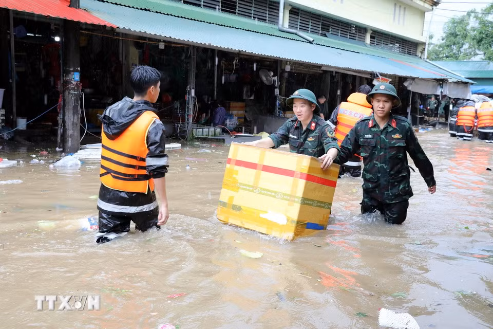 Cán bộ chiến sỹ Bộ Chỉ huy Quân sự tỉnh Lạng Sơn giúp tiểu thương di chuyển tài sản ra khỏi khu vực ngập sâu. (Ảnh: Văn Đạt/TTXVN)