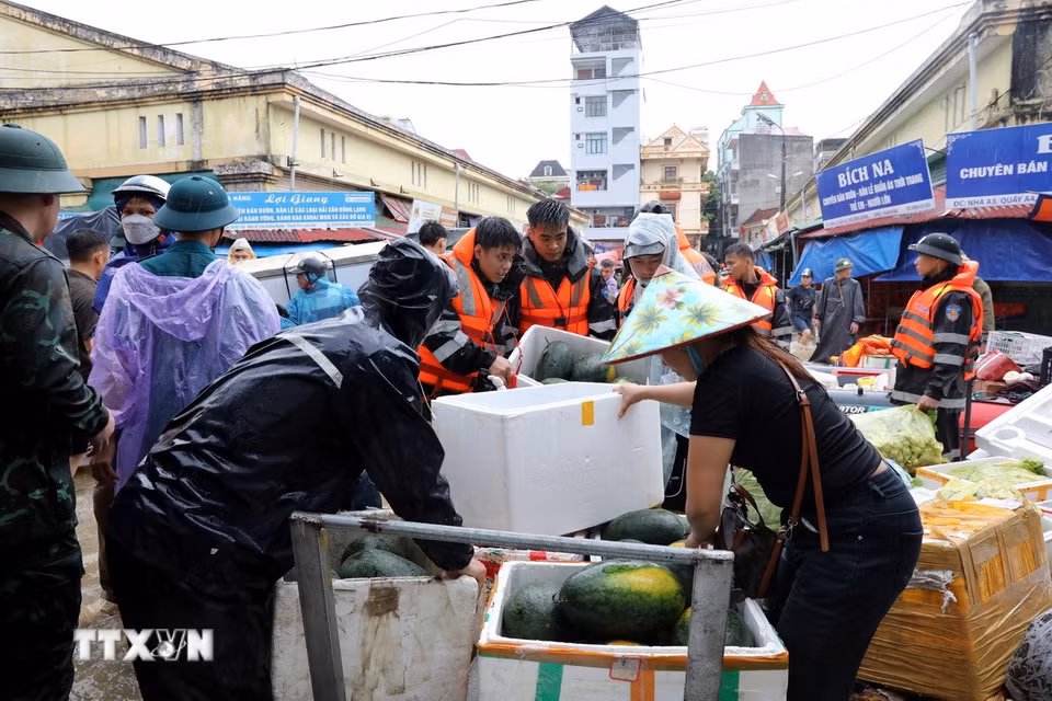 Cán bộ chiến sỹ Bộ Chỉ huy Quân sự tỉnh Lạng Sơn giúp tiểu thương di chuyển tài sản ra khỏi khu vực ngập sâu. (Ảnh: Văn Đạt/TTXVN)