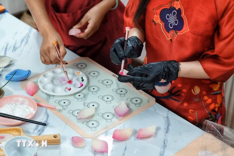 Người làm sử dụng màu thực phẩm để tạo sắc độ cho từng chi tiết bằng bột tò he, góp phần làm những cánh hoa có đường nét và màu sắc gần với hoa thật. (Ảnh: Phạm Tuấn Anh/TTXVN)