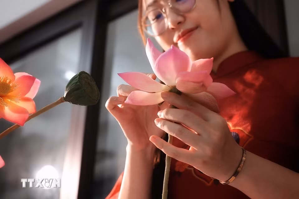 Sau khi hoàn thiện các lớp cánh, người làm tiếp tục điều chỉnh hình dáng bông sen trước khi ghép với thân và đài hoa. (Ảnh: Phạm Tuấn Anh/TTXVN)