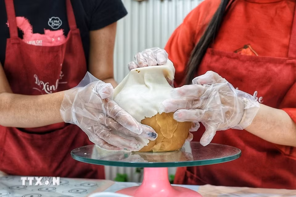 Từng bước định hình thành chiếc bình dùng để cắm những cành hoa làm bằng cách làm bánh Trung Thu. (Ảnh: Phạm Tuấn Anh/TTXVN)