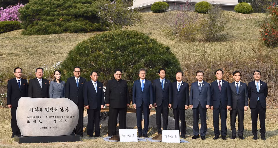 Tổng thống Hàn Quốc Moon Jae-in và nhà lãnh đạo Triều Tiên Kim Jong-un, cùng các quan chức và trợ lý cấp cao hai nước chụp ảnh lưu niệm sau khi trông cây thông hòa bình tại làng đình chiến Panmunjom ngày 27/4. (Nguồn: Yonhap/TTXVN)