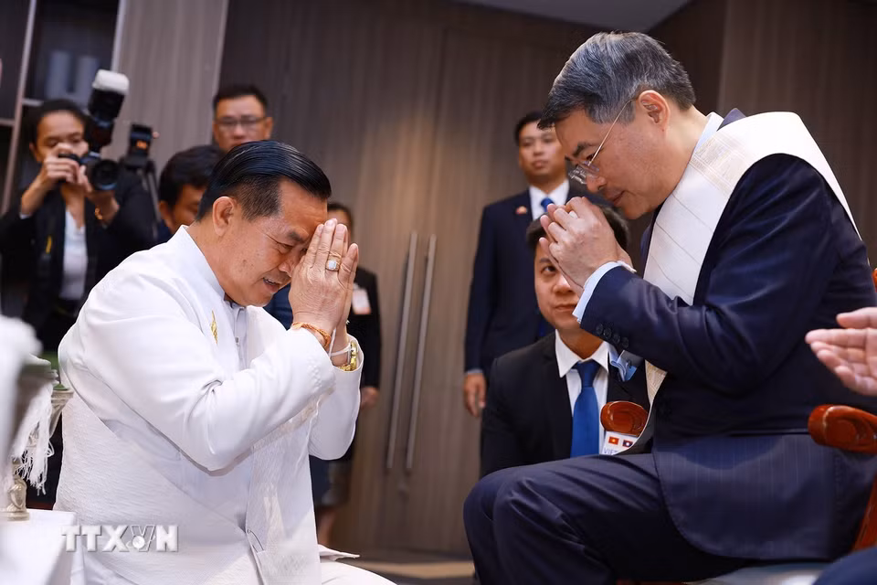 Thủ tướng Lê Minh Hưng thực hiện nghi thức buộc chỉ cổ tay truyền thống của Lào. (Ảnh: Dương Giang/TTXVN)