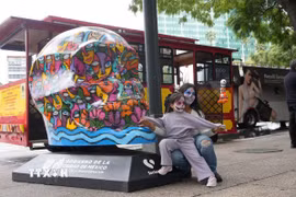 Hai mẹ con chụp ảnh cùng mô hình đầu lâu tại trung tâm thủ đô Mexico City. (Ảnh: Phi Hùng/TTXVN)