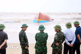 Lên phương án trục vớt tàu cá bị đánh chìm và dạt vào tại khu vực biển xã Bắc Trạch. (Ảnh: Tá Chuyên/TTXVN)
