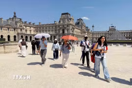 Nhiều du khách mang theo ô và nước uống khi tham quan bảo tàng Louvre trong đợt nắng nóng tại Paris, Pháp. (Ảnh: Hữu Chiến/TTXVN)