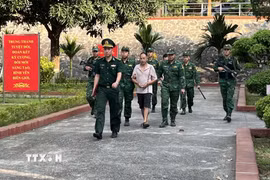Bộ đội Biên phòng tỉnh Lào Cai áp giải 2 đối tượng trong đường dây xuyên quốc gia đưa người vượt biên trái phép. (Ảnh: TTXVN phát)