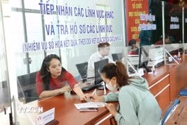 Hướng dẫn người dân làm thủ tục đăng ký hộ kinh doanh. (Ảnh: Dương Chí Tưởng/TTXVN)