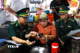 Chiến sỹ Đồn Biên phòng Cửa khẩu Mỹ Quý Tây (Tây Ninh) tuyên truyền pháp luật cho người dân tại khu vực chợ Tho Mo, đưa những quy định về biên giới, phòng, chống tội phạm đến gần hơn với đời sống. (Ảnh: Bùi Giang/TTXVN)