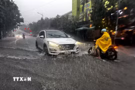 Người và phương tiện gặp nhiều khó khăn khi lưu thông qua các tuyến đường tại thành phố Đồng Hới (Quảng Trị) bị ngập sâu. (Ảnh: TTXVN phát)