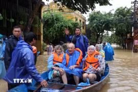 Lực lượng chức năng đưa khách nước ngoài được di chuyển tới nơi an toàn. (Ảnh: Anh Dũng/TTXVVN)