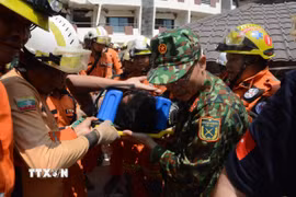 Lực lượng cứu hộ của Việt Nam, Myanmar và Thổ Nhĩ Kỳ đưa nạn nhân ra xe cứu thương. (Ảnh: Vũ Hùng/TTXVN phát)