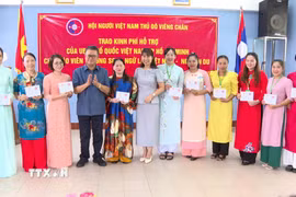 Đại diện Đại sứ quán Việt Nam tại Lào và Hội người Việt Nam thủ đô Vientiane trao quà cho các thầy cô giáo. (Ảnh: Bá Thành/TTXVN)