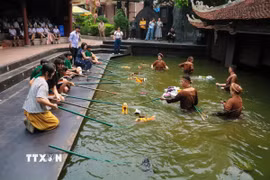 Cô giáo và các học sinh Trung Quốc thích thú trải nghiệm múa rối nước dân gian Việt Nam. (Ảnh: Phương Anh/TTXVN phát)