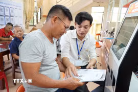 Cán bộ hướng dẫn người dân thực hiện thủ tục hành chính tại Quảng Ngãi. (Ảnh: Đinh Hương/TTXVN)