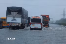 Các phương tiện di chuyển chậm qua một đoạn đường bị ngập nước (Ảnh: Hoàng Hiếu/TTXVN)