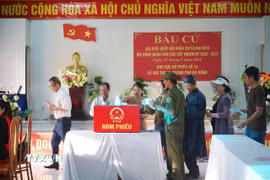 Đúng 6 giờ 30 phút, sau lễ chào cờ, hát Quốc ca, công bố thể lệ và quy chế bầu cử, cử tri xã Núi Thành tiến hành bầu cử. (Ảnh: Đoàn Hữu Trung/TTXVN)