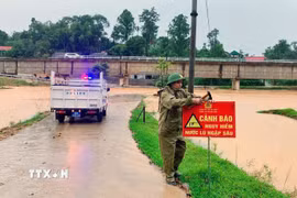 Lực lượng chức năng cắm biển báo ở cung đường ngập lụt. (Ảnh: Công Tường/TTXVN)