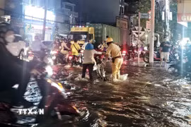 Các chiến sỹ Cảnh sát giao thông Trạm Đa Phước hỗ trợ người dân vượt qua biển nước. (Ảnh: TTXVN phát)