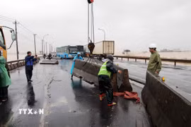 Nỗ lực khắc phục dải phân cách cứng bị trôi dạt trên Quốc lộ 1A. (Ảnh: Đỗ Trưởng/TTXVN)
