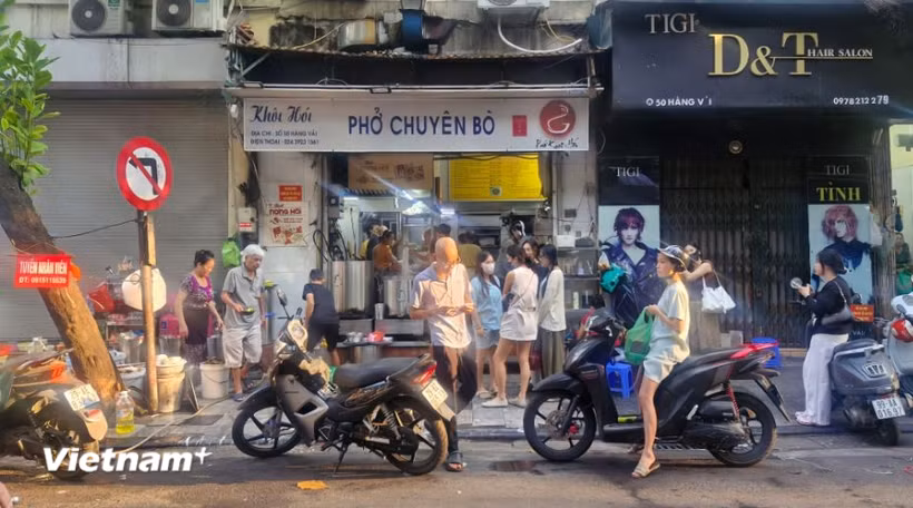 Hàng dài người xếp hàng chờ đến lượt tại một quán phở vào sáng sớm. (Nguồn: Vietnam+)