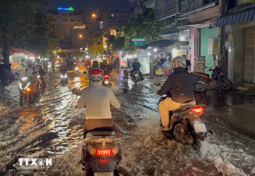 Các phương tiện lưu thông trên đường Trần Xuân Soạn, phường Tân Thuận, bị ngập do triều cường buổi tối 28/9. (Ảnh: Hồng Đạt/TTXVN)