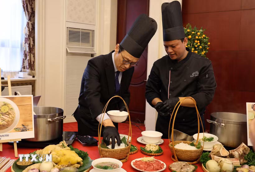 Quan chức ngoại giao tại Trung Quốc trải nghiệm cách chế biến một tô phở. (Ảnh: Hải Yến/TTXVN)