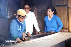 Nguyễn Thành Kiên đang giới thiệu cho du khách cách sao trà bằng chảo gang trên bếp lửa. (Ảnh: Hằng Trần/Vietnam+)