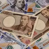 Đồng tiền mệnh giá 10.000 yen và 100 USD. (Ảnh: AFP/TTXVN)
